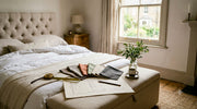 Fabric swatches, tape measure and a hand-sketched floor plan laid out on an upholstered Belsogno ottoman bed in summer morning light.