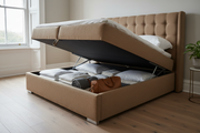 Upholstered ottoman bed with gas-lift base raised open, showing folded linens stored in the full-size compartment beneath the mattress