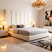 Modern bedroom with a large bed, decorative headboard, and chandelier.