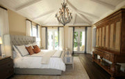 Luxurious bedroom with a large bed, wooden wardrobe, and chandelier.